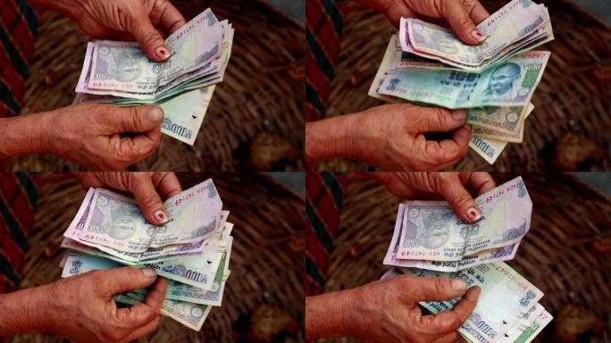 贫困概念。可怜的女人数着印度卢比的钞票，特写