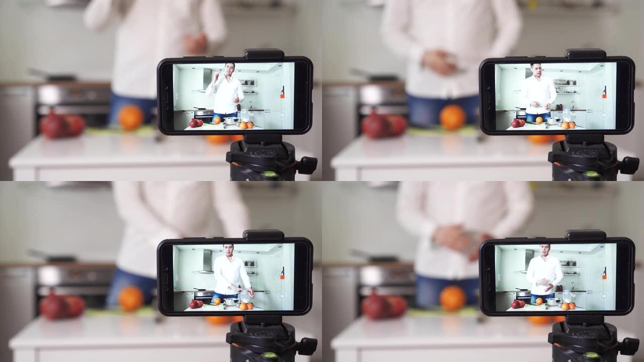 男人在厨房里用水果拍摄视频。Vlogging概念。