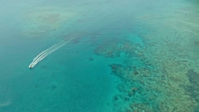 令人惊叹的空中无人机图像，一艘小渔船进入偏远偏远的热带岛屿上清澈的蔚蓝海水中的珊瑚礁旁边的通道中的海