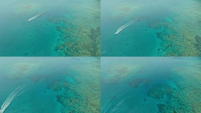 令人惊叹的空中无人机图像，一艘小渔船进入偏远偏远的热带岛屿上清澈的蔚蓝海水中的珊瑚礁旁边的通道中的海