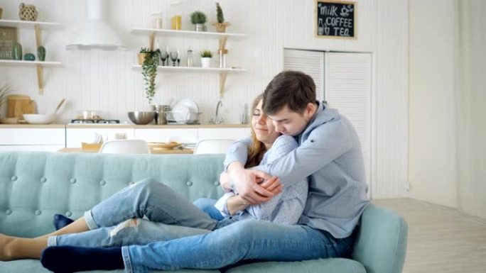 男人拥抱坐在沙发上并在厨房接吻的女士