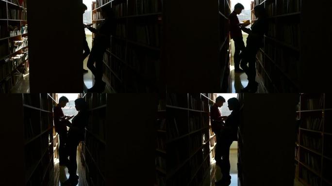 剪影大学生在图书馆的书架之间交谈