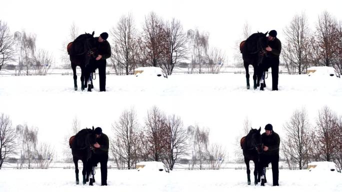 冬天，残疾人站在雪原上的黑马附近。人抚摸着马的枪口。男人有假肢而不是右腿。他学会了骑马，海马疗法。动
