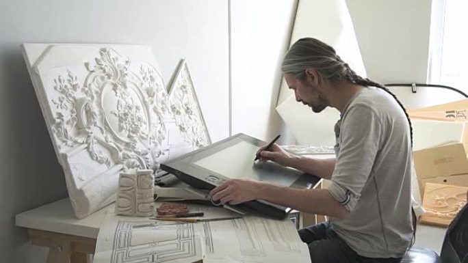 成熟的设计师将白色石膏造型与花卉装饰品复制到大型图形平板电脑上