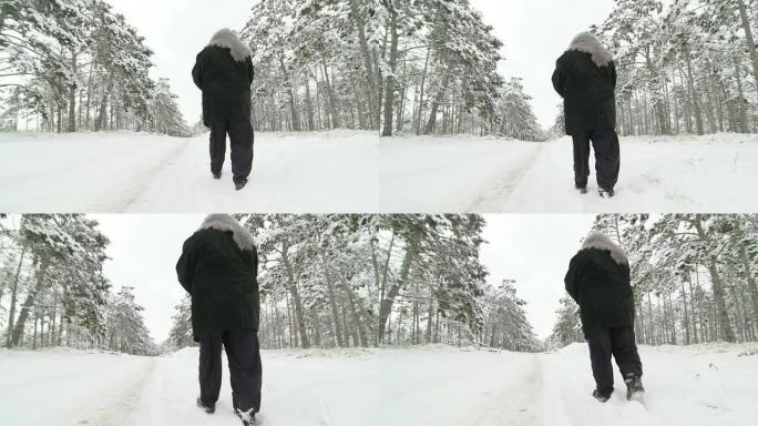 孤独的高级妇女在雪地里穿过冬天的树林