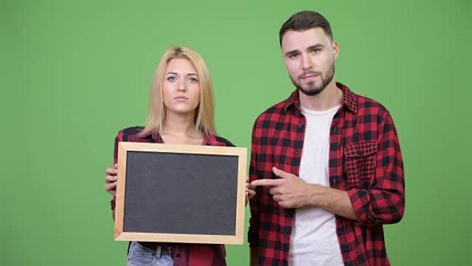 年轻夫妇拿着黑板，一起指指点点