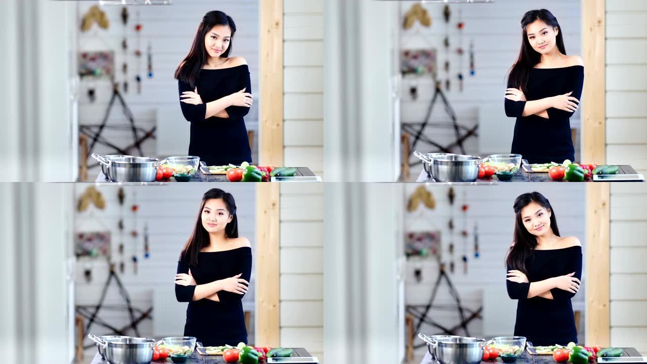 美丽的年轻亚洲女孩在烹饪时双手交叉站着看着相机