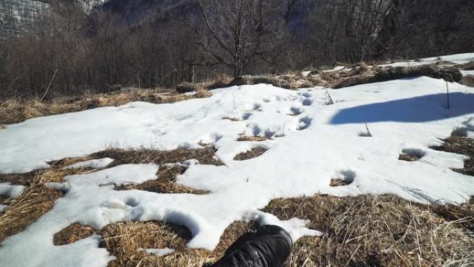 POV，单人旅行者，春天，在雪地里休息的男性游客，男人的脚，往下看，一双靴子，放松
