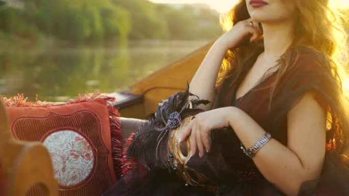 奢华面具，羽毛在日落时漂浮在船上的狂欢节礼服的华丽女人的手中。