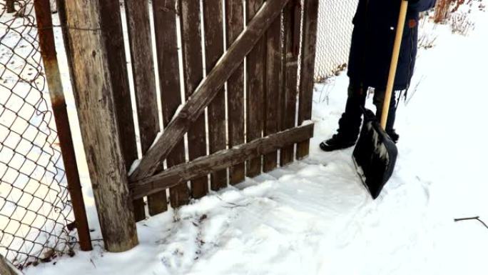 女人在花园大门周围挖雪