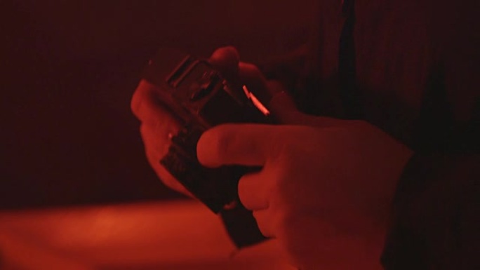 摄影师在红色暗室里拿着老式相机