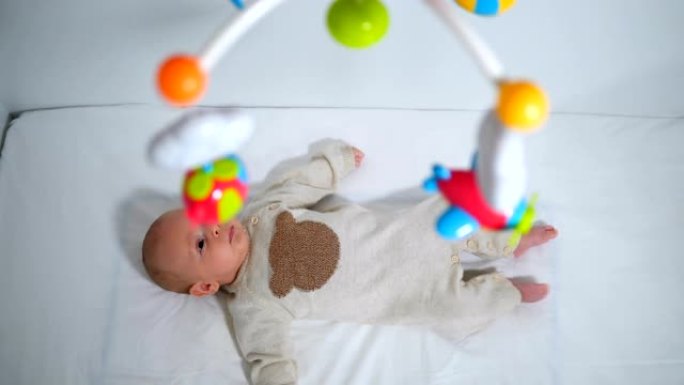 无辜男婴看着婴儿床上悬挂的玩具的高角度视图