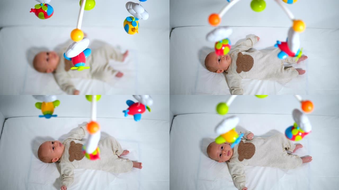 无辜男婴看着婴儿床上悬挂的玩具的高角度视图