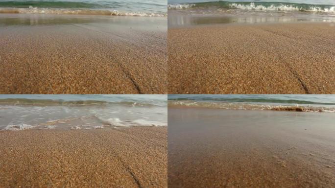 地面视频-靠近海水冲洗沙子，在阳光下迅速干燥。镜头上很少有滴水来强调水。