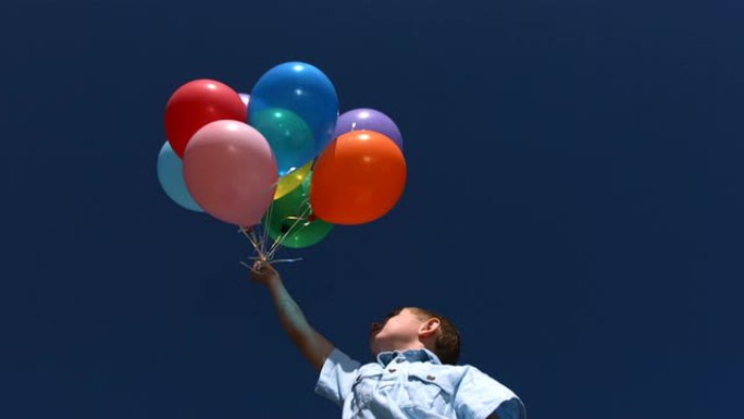 小男孩让气球进入天空，慢动作
