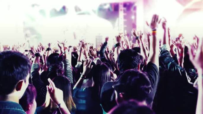 节日人群后视音乐会人群的剪影在明亮的舞台灯光上举手