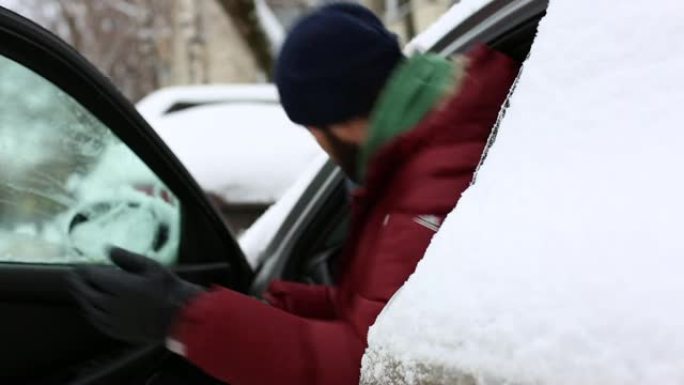 男人正坐在车里。周围有很多雪。男人穿着冬衣和帽子。