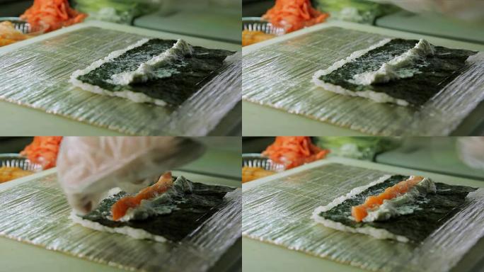 厨师在煮寿司卷时撒奶油干酪并放鲑鱼