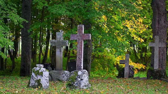 古老的石头在坟墓上十字架，周围有秋天的树木