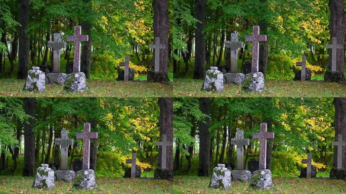 古老的石头在坟墓上十字架，周围有秋天的树木