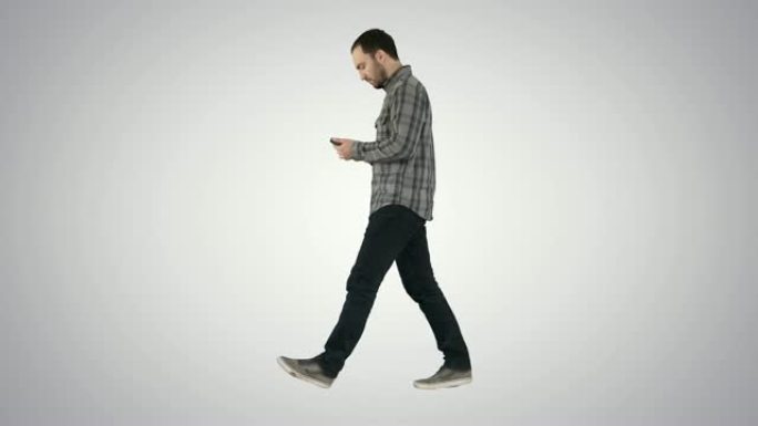 年轻聪明的休闲男人在渐变背景上的手机上行走和阅读消息