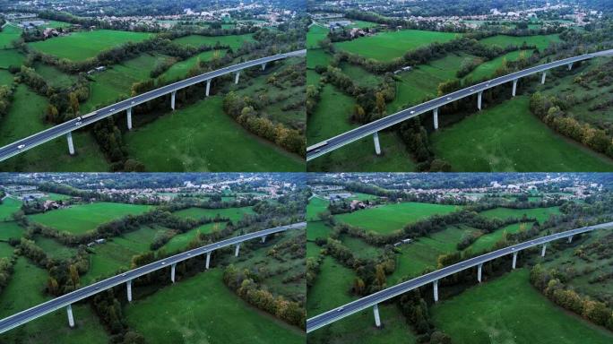 法国一座桥上高速公路的全景鸟瞰图。道路周围只有草地和树木。在阳光下的道路上行驶的汽车和卡车。