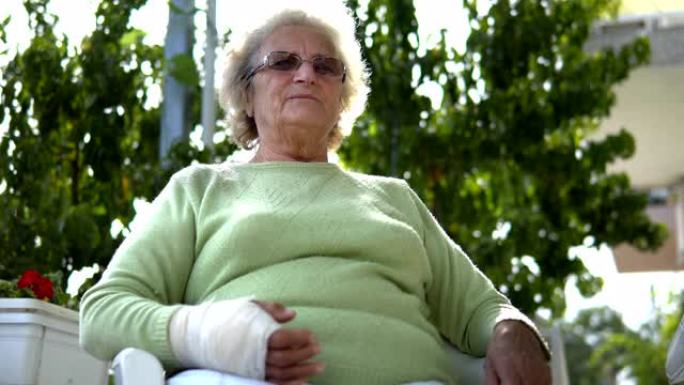 老年老妇人的肖像受伤，手臂受伤，坐着说话