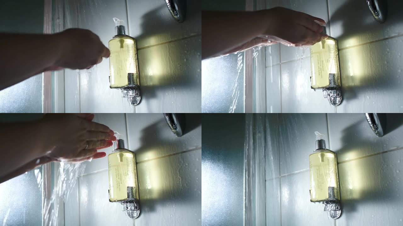 手在淋浴流下推一个装有肥皂的容器