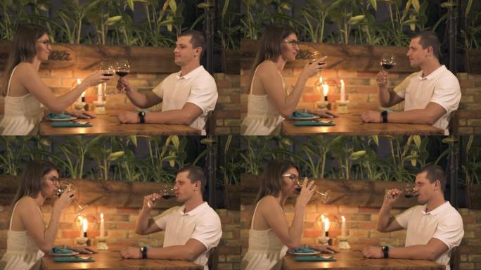 幸福的夫妻在餐厅里用蜡烛在浪漫的晚餐上喝红酒。男人和女人在餐厅浪漫约会时喝杯红酒