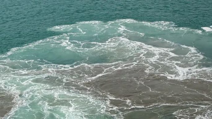 海蓝宝石海浪从船上的工作引擎沸腾并产生泡沫，海鸥在海上飞行