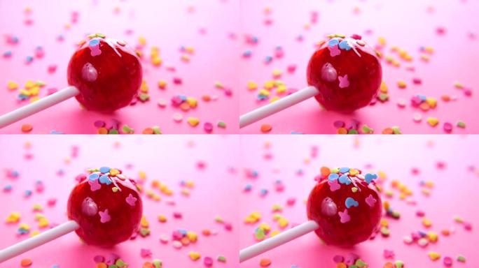 粉色圆形棒棒糖特写粉色背景。小动物形象形式的彩釉散布在红色糖果上。