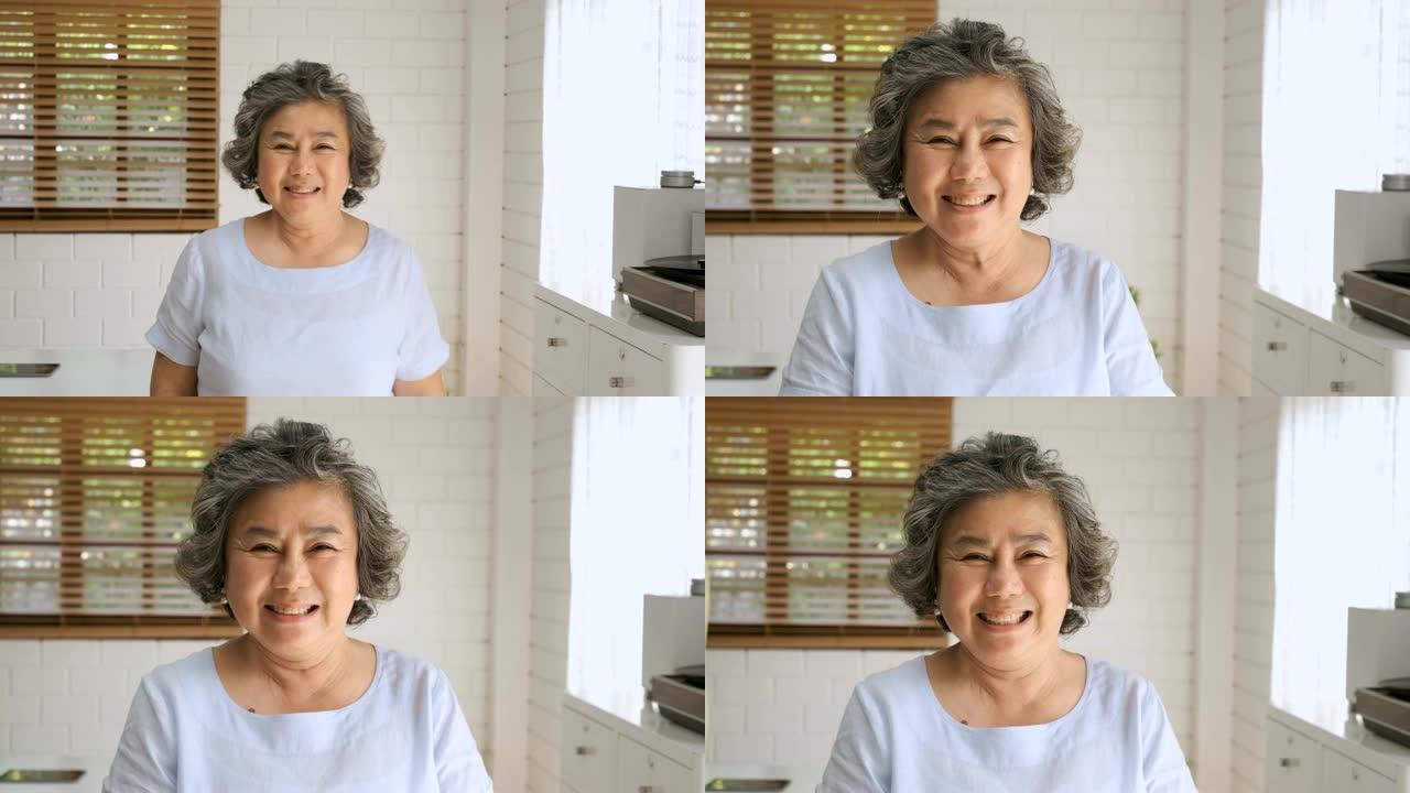 亚洲高级女性在家里的客厅里看着相机微笑的肖像。在家中的快乐衰老概念
