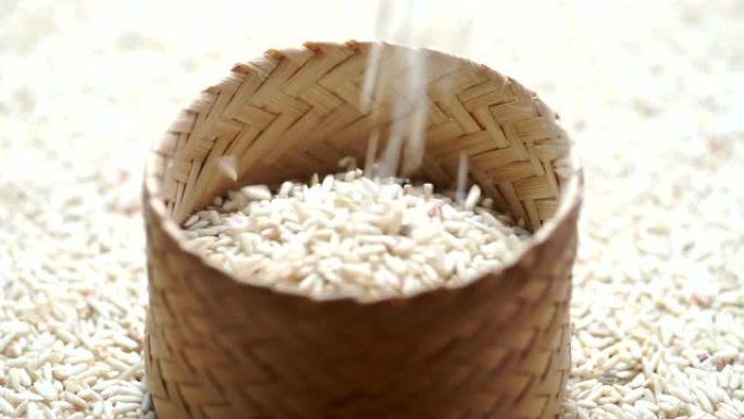 在大米背景下，将生糯米倒入竹编中。
