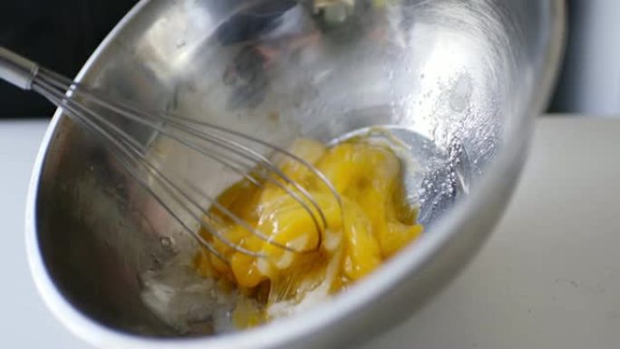 女人准备自制煎蛋卷和打蛋器混合的慢动作作物镜头。