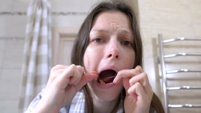 昏昏欲睡的女人宿醉醒来，在浴室里用牙线刷牙。