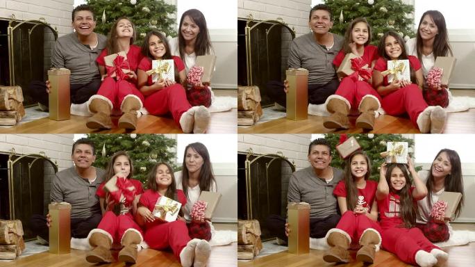 一家人坐在圣诞树下，女儿们把礼物放在头上