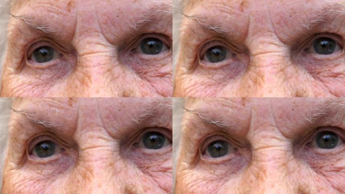 祖母带着悲伤的景象看着镜头的肖像。闭上老年妇女的灰色眼睛，周围有皱纹。高级女士的悲伤表情。