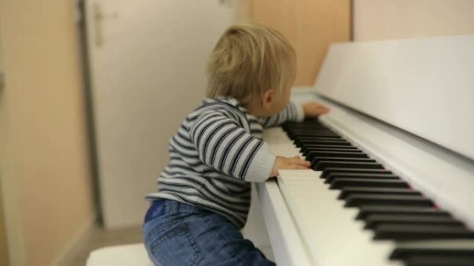 甜美积极的学步儿童弹钢琴。幼儿早期音乐教育。