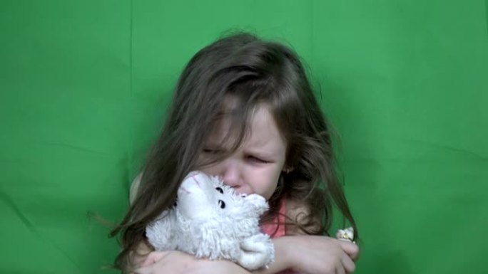 小女孩哭着拿着一个柔软的玩具。