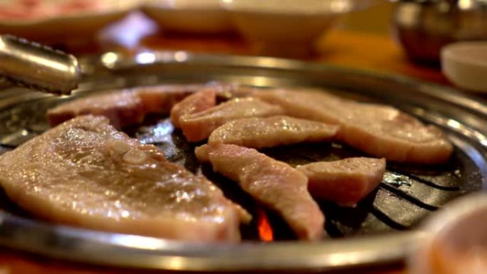 韩国食物-在炉子上烹饪切片烤猪肉烧烤风格的特写