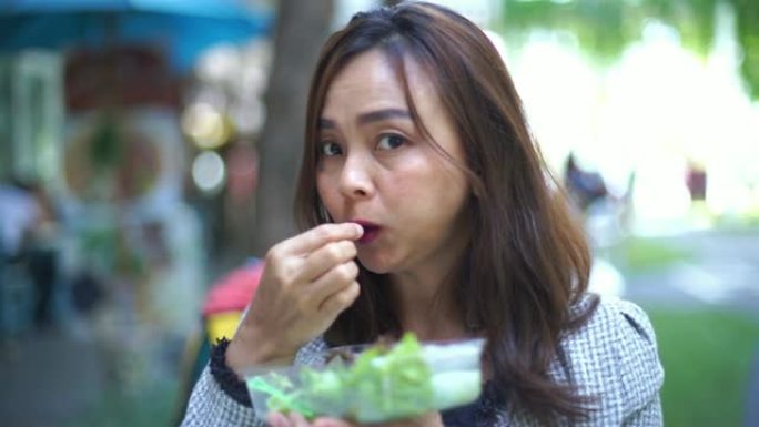 亚洲成熟女人表现出吃沙拉卷，竖起大拇指