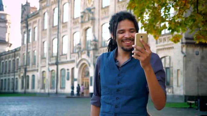 有吸引力的非裔美国学生，在大学背景下使用智能手机在视频聊天中使用辫子聊天。