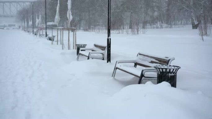 降雪下的冬季街道上的长凳和路灯