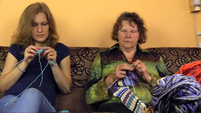 高年级奶奶和年轻孙女交谈和编织