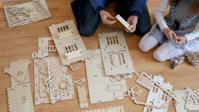 小女孩和父亲一起建造木制玩具屋