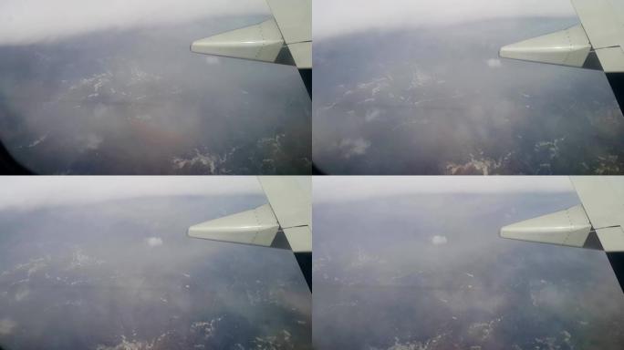 乘客的POV从飞机的窗户越过飞行中的低云，飞越威尼斯泻湖的岛屿。飞机，飞行，飞机机翼