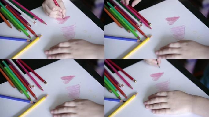 一个孩子的手在自制明信片上画了一个红色的铅笔心。儿童教育