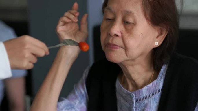 年轻的亚洲妇女为祖母喂食食物