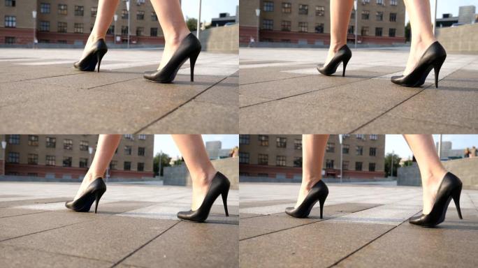 阳光明媚的日子，穿着黑色高跟鞋的苗条女性腿在城市广场散步。穿着高跟鞋的年轻女商人的脚在城市街道上。低