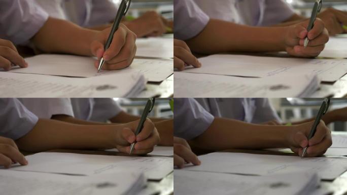 手握笔书写笔记本的学生在课堂上学习，教育理念。